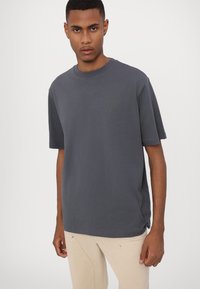 Gray crew-neck t-shirt with short sleeves, made of cotton, features a subtle logo in a darker shade on the left chest area.