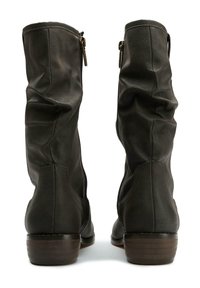 Brown leather knee-high boots with a slouchy design, side zippers, and a stacked heel. Textured surface with visible stitching details.