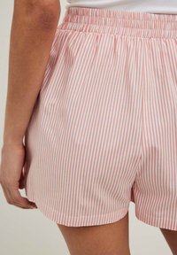 Rosa och vita randiga shorts med elastiskt midjeband, tillverkade av lättviktsmaterial, med en avslappnad passform och rundad nederkant.