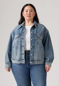 Light blue denim jacket with a boxy design, button closures, two chest pockets, and a classic collar. Paired with high-waisted blue jeans.