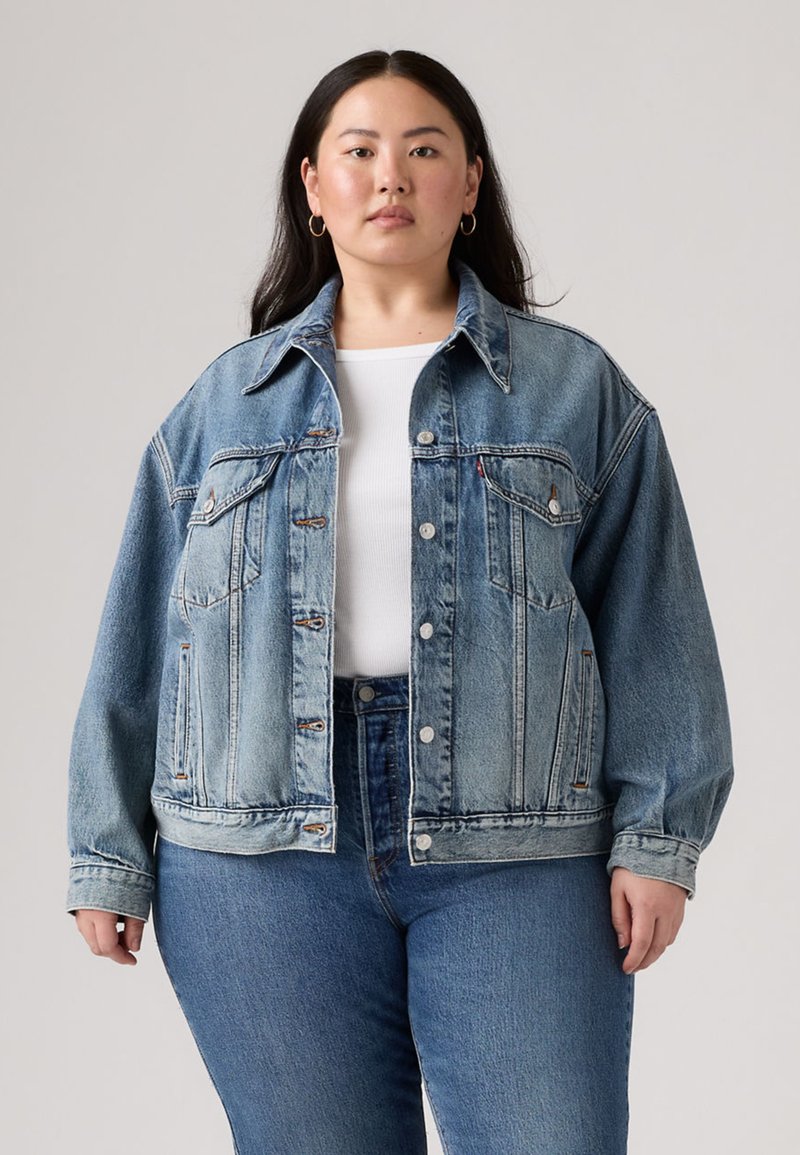 Light blue denim jacket with a boxy design, button closures, two chest pockets, and a classic collar. Paired with high-waisted blue jeans.