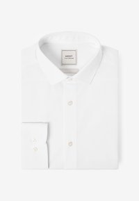 Camisa blanca de vestir doblada con cuello clásico y puños abotonados, con una etiqueta "NEXT Tailoring" en el interior del cuello.