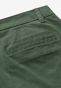 Groene katoenbroek met een achterzak met een nette afwerking en subtiele stikdetails. Soepele textuur met een gestructureerde taille.