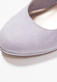 Lavendelmockaskor med rund tå och låg design. Har en slät, glänsande innerfoder och subtila sömnadsdetaljer längs kanten.