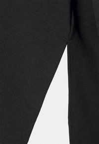 Leggings negros hechos de una mezcla de algodón elástico, con un diseño elegante, costuras visibles y una forma ajustada en los tobillos.