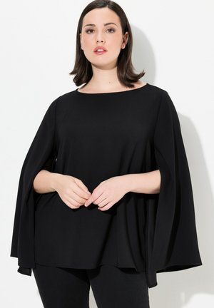 Zwarte cape-stijl top met een ronde hals, zachte stof en brede mouwen. Ontworpen met een losse pasvorm en een gladde textuur voor comfort.