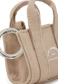 Bežna mini torba iz teksturirane tkanine, s dvema kratkima ročajema in priloženim srebrnim ključem. Logotip je natisnjen na sprednji strani.