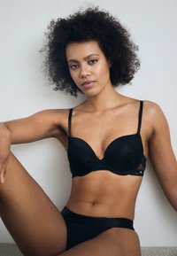 Zwarte bh met kant, verstelbare bandjes, en gevormde cups met een gladde afwerking. Gecombineerd met bijpassende zwarte high-waisted slip.