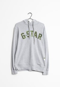 Šedá mikina s kapucí, s velkým zeleným nápisem "G-STAR". Vyrobena z měkkého materiálu s žebrovanými manžetami a dolním lemem. Visí na černém háčku.