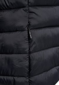 Schwarze Steppjacke mit einem gesteppten Design, das eine glatte, glänzende Textur aufweist, sowie einem Reißverschluss vorne mit einem kleinen Zipperanhänger.