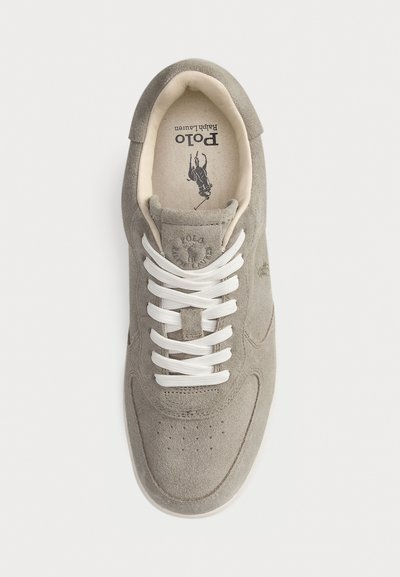 Sneaker grigia in suede con lacci bianchi, punta rotonda e perforazioni minime. Presenta un logo sulla linguetta e un branding sottile sui lati.
