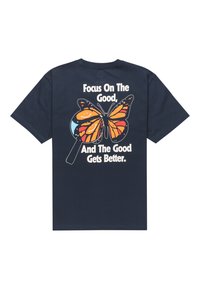 Camiseta de algodón azul marino con un gran diseño de mariposa colorida y el texto "Enfócate en lo bueno, y lo bueno mejora." en la parte de atrás.