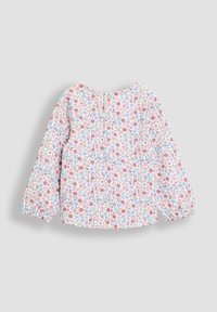 Blusa de manga larga para niño pequeño con fondo blanco y pequeño patrón floral en rojo, azul y rosa, con cierre de botón en la parte trasera.
