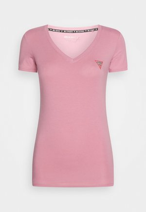 Camiseta rosa ajustada para mujer con cuello en V, mangas cortas y pequeño logo rojo de Guess en el pecho izquierdo.