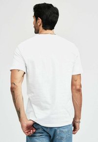 Vit bomullströja med klassisk rundhals och korta ärmar, med en slät textur och inga synliga mönster eller grafiska motiv.