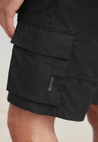 Fekete cargo shorts, texturált anyagból készült, több zsebből áll, és az oldalon egy szőtt márkacímke található.
