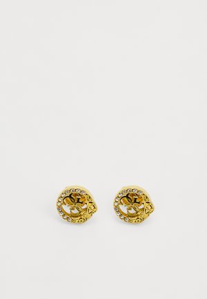 Złote metalowe kolczyki o okrągłym kształcie z kwiatowymi akcentami i obrzeżem z przezroczystych cyrkonii. Skomplikowany wzór w centrum.