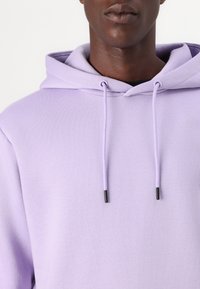 Lavender hoodie with a drawstring, featuring black aglets. Made of soft fabric with a smooth texture, showing a relaxed fit around the neck.