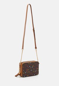 Borsa a tracolla in pelle marrone con un frontale in tessuto a fantasia che presenta uccelli colorati, tracolla in catena dorata e chiusura a zip sulla parte superiore.