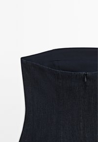 Tmavě modrý denový korzet se strukturovaným designem, který má hladké vnitřní podšívání a zapínání na zip na zadní straně.