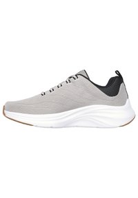 Scarpa sportiva grigia con upper in tessuto testurizzato, suola bianca imbottita e dettaglio nero sul tallone; presenta un design con lacci e un tassello per il sollevamento.