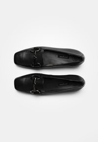 Černé kožené mokasíny se čtveratým špičkou, s kovovým detailem přezky a hladkým povrchem. Viditelná vnitřní etiketa.