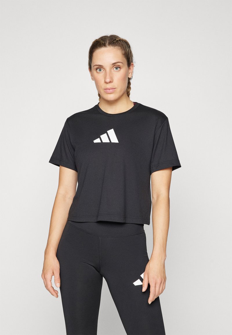 Svart cropped t-skjorte med rund hals og korte ermer, med en hvit diagonalt stripe-logo på brystet. Sorte leggings med matchende logo.