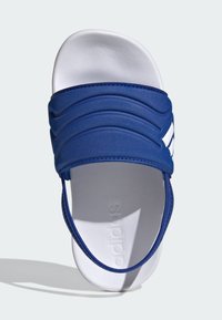 Modra natikača s teksturirano gumijasto zgornjo stranjo z vodoravnimi utori in belim podplatom. Blagovna znamka vtisnjena na vložku.