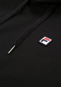 Felpa nera con un tessuto testurizzato. Presenta un piccolo logo ricamato bianco, rosso e blu. Include stringhe nere coordinate con estremità in metallo.