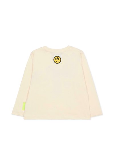 Camicia a maniche lunghe color crema chiaro con un emblema di faccina felice nera circolare e un piccolo tag verde neon sull'orlo. Materiale in cotone morbido.