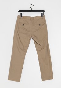 Khaki kalhoty s přímým střihem, dvěma zadními kapsami na knoflíky a hladkým povrchem. Visí na černém plastovém háčku.