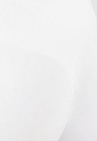 Leggings blancos sin costuras con una textura suave y una cinturilla acanalada, que presentan un diseño ajustado que enfatiza el contorno y la elasticidad.