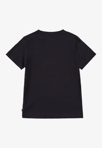 Melna kokvilnas T-krekls ar īsām piedurknēm, apaļu kakla izgriezumu un taisnu piegriezumu. Apakšmalā ir neliela zīmola logotipa birka.