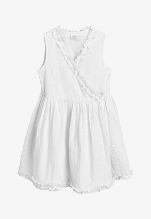Robe bébé blanche sans manches avec motif floral ajouré, bordure à volants le long du décolleté en V et de l'ourlet, taille froncée et devant croisé avec bouton.