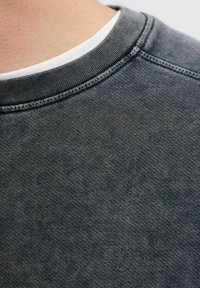 Donkergrijze crewneck sweatshirt met een textuur van gebreide stof en een contrasterende witte binnenkraag. Geen zichtbare logo's of patronen.