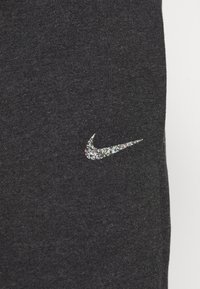 Černá látka s hladkým povrchem, na boku s lesklým, barevným logem Nike swoosh.