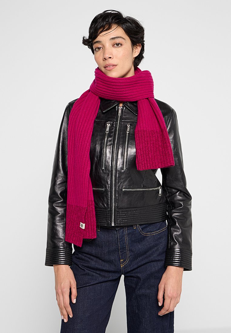 Fuchsia Rippenschal aus weichem Material, locker über einer schwarzen Lederjacke getragen, mit strukturiertem Finish und breiten Enden.
