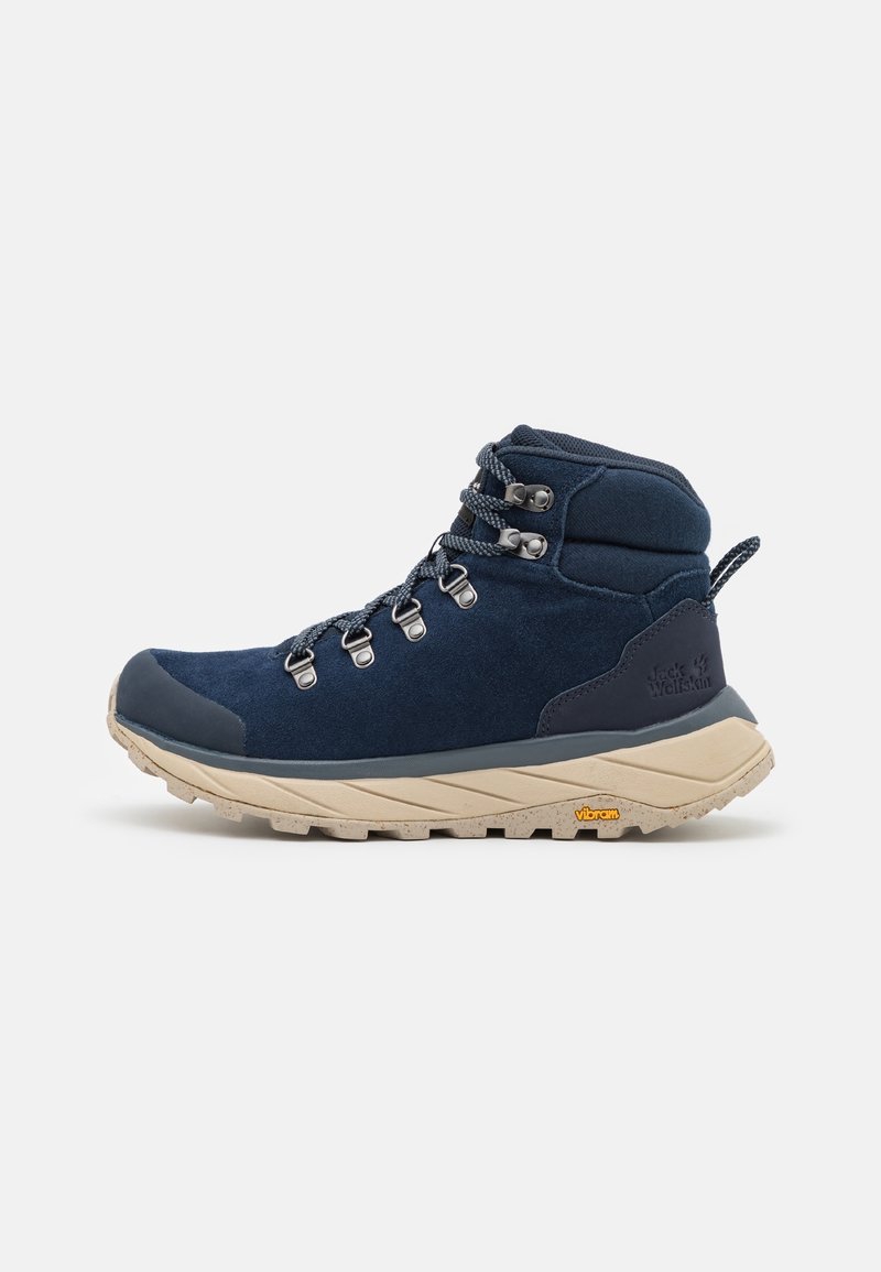 Botte de randonnée en daim bleu marine avec accents gris, œillets métalliques, col rembourré et semelle Vibram beige pour l'adhérence. Lacets visibles à l'avant.