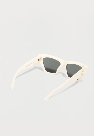 Λευκά ορθογώνια γυαλιά ηλίου με σκοτεινούς φακούς, διπλωμένα και τοποθετημένα σε ανοιχτό γκρι επιφάνεια.