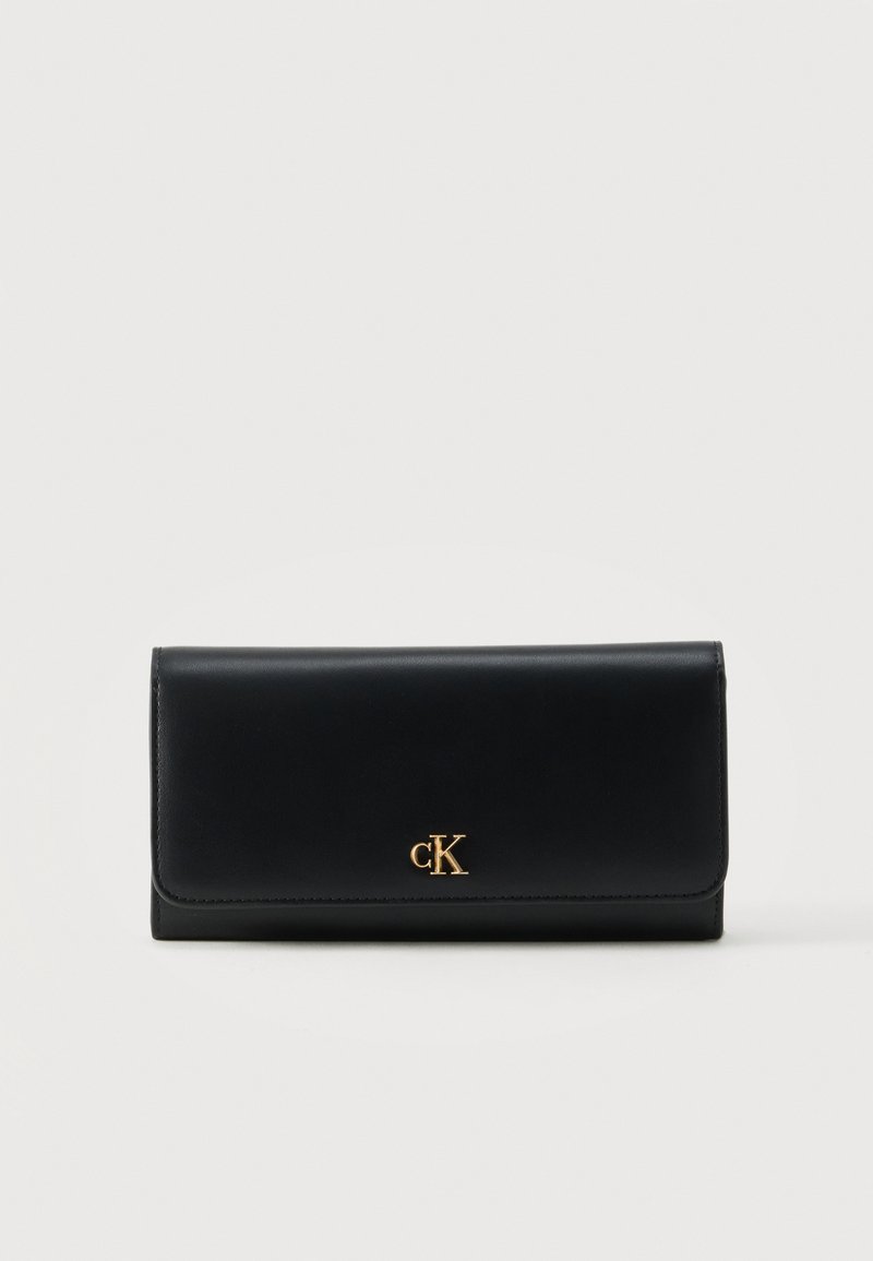Portefeuille en cuir noir avec logo CK doré centré sur le rabat avant, forme rectangulaire sur fond clair uni.