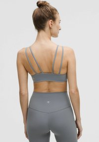 Grijze sportbeha met smalle, verstelbare bandjes en een strak ontwerp, gecombineerd met hoge taille legging in hetzelfde materiaal en kleur.
