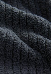 Tissu gris texturé avec une surface douce et pelucheuse, comportant des motifs à côtes verticales. Convient pour une utilisation dans les textiles et la tapisserie.