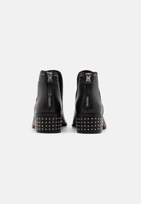 Bottines en cuir noir avec des accents en clous argentés sur le talon et des zips contrastants à l'arrière. Design de talon épais robuste.