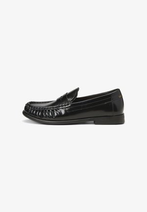 Mocassins en cuir noir avec un bout texturé et froncé, et une finition lisse. Petit talon avec un design minimaliste et une branding subtil sur le côté.