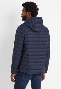 Navy blue puffer jacket with a hood, featuring quilted sections, ribbed cuffs, and a logo patch on the left shoulder.