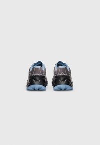 Ein Paar schwarz-hellblaue Sportschuhe mit geometrischem Muster an den Fersen, von hinten gegen einen weißen Hintergrund betrachtet.