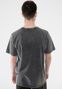 Gray cotton t-shirt with a relaxed fit, crew neckline, and short sleeves. Features faded texture and visible stitching details.