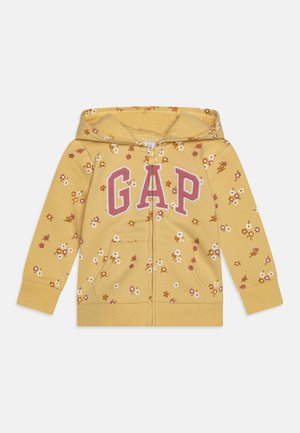 Gul børne-hoodie med lynlås og hætte, lille hvid, pink og brun blomsterprint samt store pink GAP-bogstaver over brystet.
