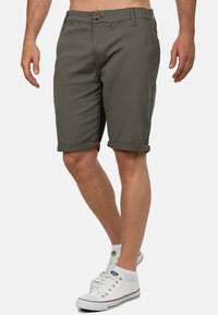 Heren groene shorts met opgerolde pijpen, voorzien van rode stikselaccenten en een knoopsluiting, gemaakt van een gladde, duurzame stof.