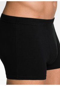 Boxer in cotone nero con design aderente, texture liscia e cuciture piatte per il comfort. Nessun motivo o decorazione visibile.